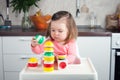 Construction a 2 year old girl with long hair plays with a designer at home, builds towers, rejoices at successes Royalty Free Stock Photo