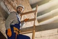 Construction you can count on. Handsome workman in blue overalls and hard hat looking at camera, climbing down the Royalty Free Stock Photo