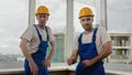 Constructiona workers in helmets comic dancing looking to camera. Royalty Free Stock Photo