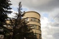 Constructivist building and pine trees with cloudy sky in background. Moscow, Russia.