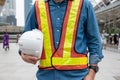 Constructor man in work vest holding safety helmet at workplace