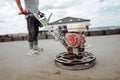Constrution site worker using helicopter power tool and polishing sand and cement screed floor Royalty Free Stock Photo
