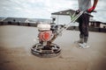 Constrution worker installing and polishing sand and cement screed floor using power tool