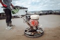 Constrution worker performing and polishing sand and cement screed floor using power tool Royalty Free Stock Photo