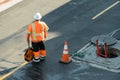 Constuction flag person standing by manhole