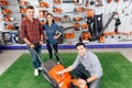 A consultant in a garden tools store shows a guy and a girl a lawn mower. Royalty Free Stock Photo