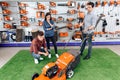 A consultant in a garden tools store shows a guy and a girl a lawn mower. Royalty Free Stock Photo