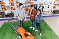 A consultant in a garden tools store shows a guy and a girl a lawn mower. Royalty Free Stock Photo