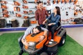 A consultant in a garden tools store shows a guy and a girl a lawn mower. Royalty Free Stock Photo