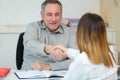 consultant shaking hands with young woman across office desk Royalty Free Stock Photo