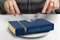 Consume knowledge concept, hands cut book on plate Royalty Free Stock Photo