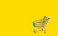 Shopping trolley on yellow background and some copy space.