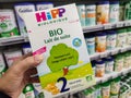 A consumer chooses a box of Hipp brand baby milk from the baby food section of a supermarket