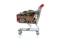 Consumerism concept with shopping trolley full of coins on white background