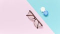 Contact lens case and glasses on blue-purple background. Concept of choice the way vision correction