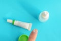 Contact lens on finger, tube of eye ointment and small bottle of eye drops on light blue background..Top view. Royalty Free Stock Photo