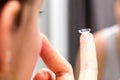 Contact lens held on finger of young face in blurred foreground