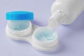 Contact lenses in container with solution bottle o on pastel purple background