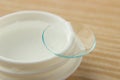 Contact lenses for the eyes and a white container with a solution on a wooden table