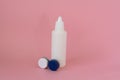 Contact lens case and bottle of solution on pink background