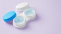 Contact lenses in white case with solution liquid on pastel purple background
