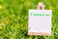 Contact us communication concept. Sign plate with words Contact us in the green grass nature meadow. Royalty Free Stock Photo