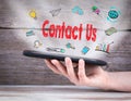 Contact Us. Tablet computer in the hand. Old wooden background Royalty Free Stock Photo