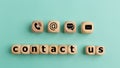 Contact us text on wooden cubes on a blue background. Wooden cube symbol telephone, mail, address, and mobile phone. Website page Royalty Free Stock Photo