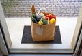 Contactless food delivery service concept. Paper bag with groceries delivered and left outside at entrance door. View from inside Royalty Free Stock Photo