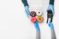 Contactless order payment during coronavirus epidemic. Deliveriman in rubber gloves gives box of brightly colored donuts