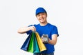 Contactless payment, shopping and home delivery concept. Smiling pleasant asian courier in blue uniform bring client Royalty Free Stock Photo