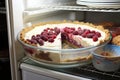 Container with berry pie in the refrigerator. Frozen semi-finished baked goods with juicy berries and cream for long