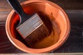 A container with brown paint and a brush on a blue board. Royalty Free Stock Photo