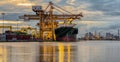 Container Cargo freight ship with working crane bridge in shipyard at dusk Royalty Free Stock Photo