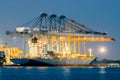 Container Cargo freight ship with working crane bridge in shipyard at dusk Royalty Free Stock Photo