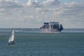 Container carrier ship and a small yacht underway.