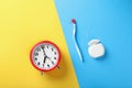 Container with dental floss, toothbrush and alarm clock on color background, flat lay Royalty Free Stock Photo