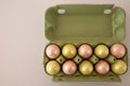 A green container for chicken eggs filled with pink and yellow Easter eggs. on a white background Royalty Free Stock Photo