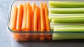 A container filled with fresh celery sticks and sliced carrots, ideal for healthy snacking Royalty Free Stock Photo