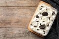 Container of ice cream with chocolate sandwich cookies on wooden background, top view. Royalty Free Stock Photo