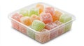 A container made of transparent plastic holds an assortment of colorful sweets on a white surface Royalty Free Stock Photo