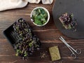 A container with micro greenery and a bowl with nasturtium leaves on a dark wooden background. Flatlay on a dark wooden