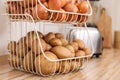 Container with potatoes and onions on kitchen counter. Orderly storage Royalty Free Stock Photo