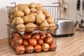 Container with potatoes and onions on kitchen counter, space for text. Orderly storage Royalty Free Stock Photo