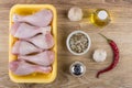 Container with raw chicken legs, spices, salt, chili pepper, gar Royalty Free Stock Photo