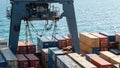 Container ship crane unloading goods with stacked containers on the shimmering sea Royalty Free Stock Photo
