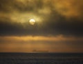 Container ship in the distance at sunset with sun visible Royalty Free Stock Photo