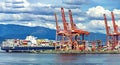 Container ship unloads in the port of Vancouver, red sea cranes and colorful containers on the background of cloudy sky Royalty Free Stock Photo