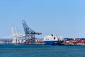 A container terminal in Jersey City, NJ with gantry cranes and a roll on, roll off RoRo ship, unloading vehicles