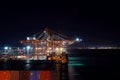 Container terminal in night under cargo operation with illuminated bridge in Pusan, South Korea.